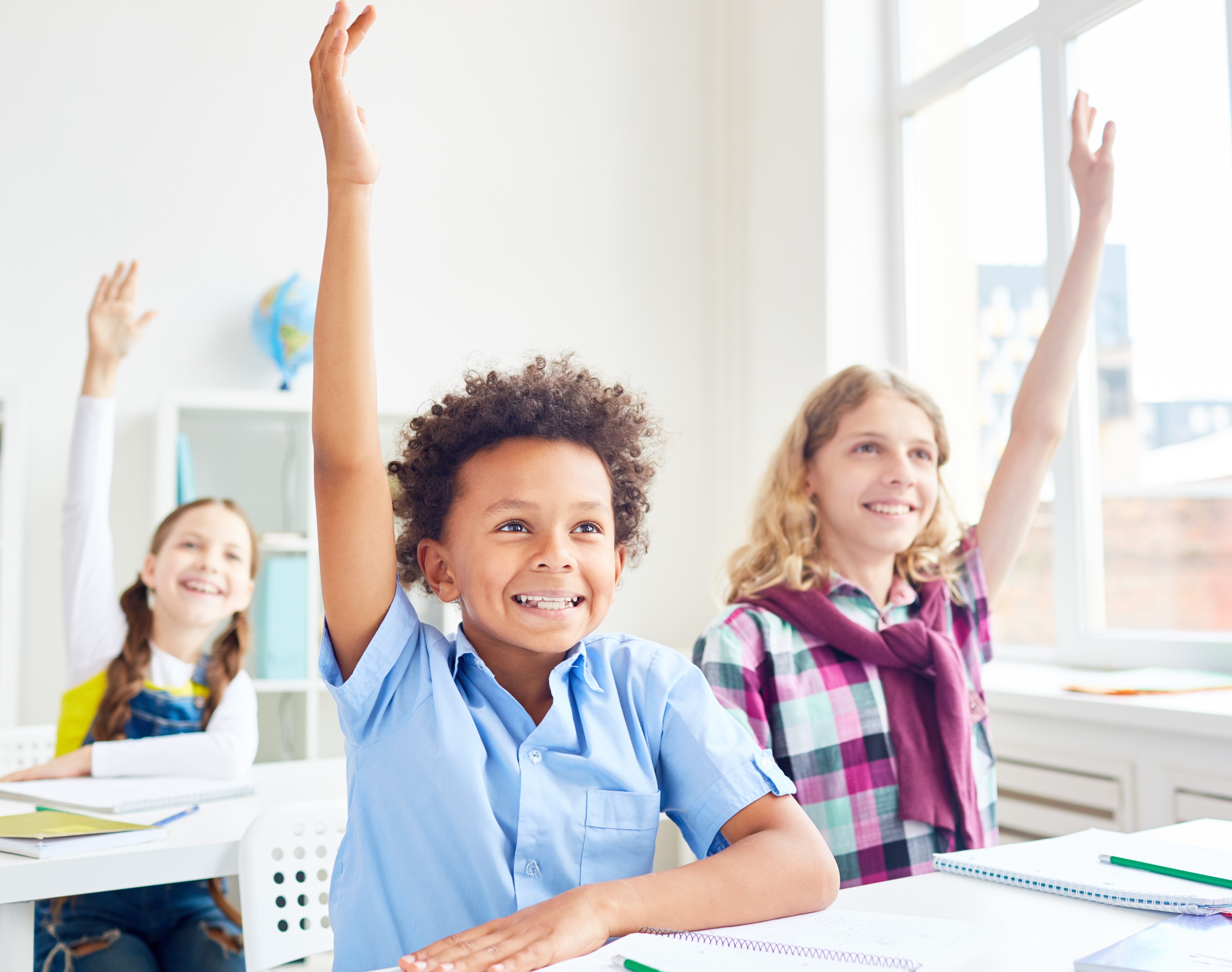Engaged elementary students raising hands during a reading comprehension lesson