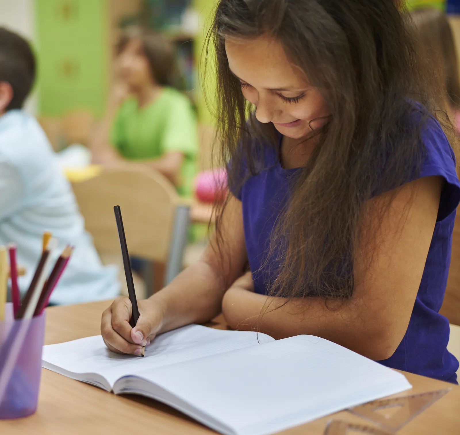 Girl writing in a notebook at her classroom desk