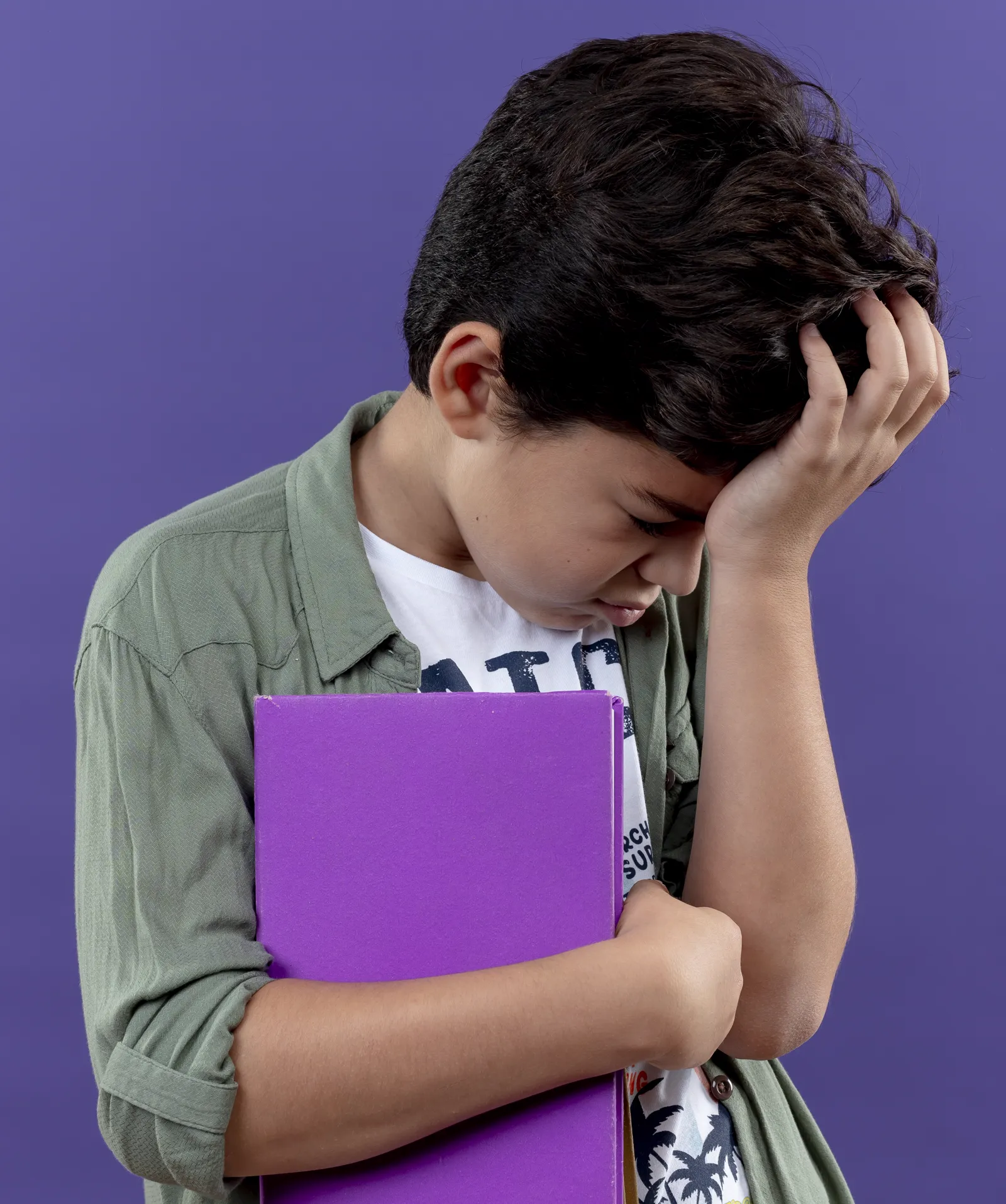 Boy holding a purple book, hand on his head