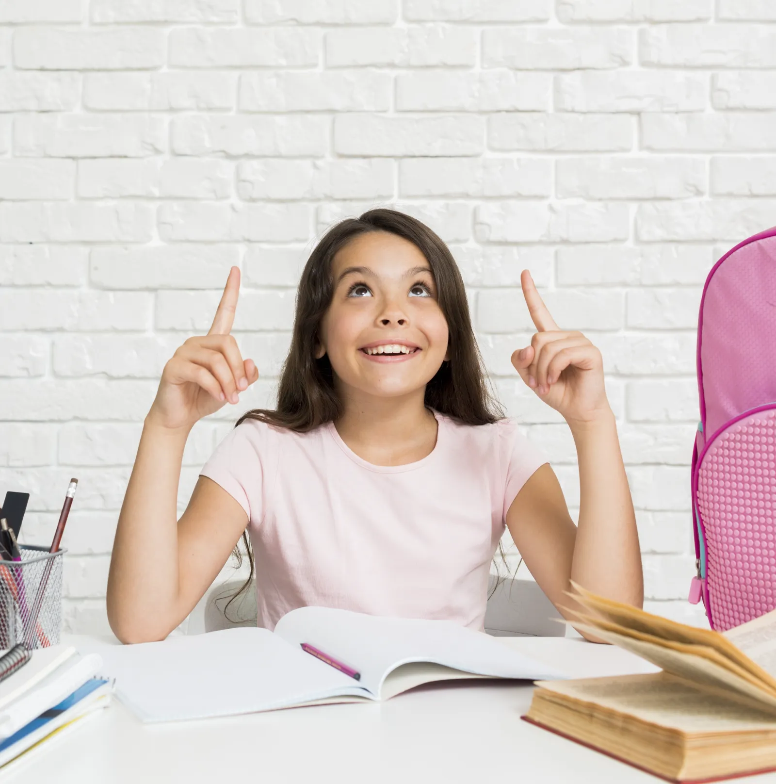 Smiling girl at her desk pointing up as an idea comes to her